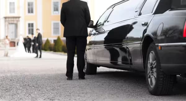 Wedding chauffeur opening a luxury vehicle door for a couple